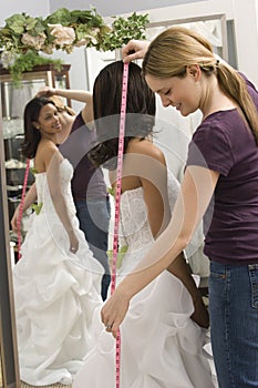 Seamstress measuring bride.