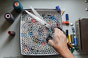 A seamstress pulls a pair of scissors out of a box with skeins of colored threads.Sewing industry