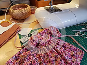 Seamstress sews a doll dress