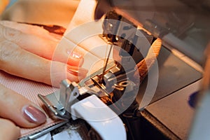 Seamstress sews fabric clothes on a sewing machine