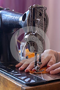 Seamstress sews on a retro sewing machine.