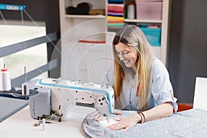 Seamstress smiling woman working with sewing machine in workshop