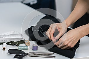 Seamstress is stitching zipper to black wide-leg pants