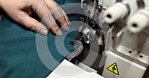 Seamstress uses overlock machine to secure fabric edges