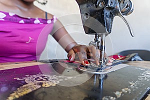 Seamstress using her black sewing machine to do African dresses