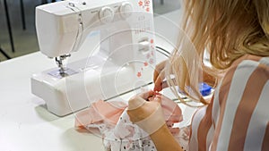 Seamstress at work in workshop sewing clothes on sewing machine