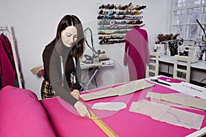 Seamstress working with sewing pattern on table in tailor shop
