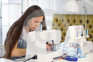 Seamstress works sewing on sewing machine in tailoring workshop business.