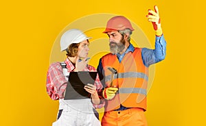 Search best solution. couple looking at a blueprint. woman and man wear safety hardhat. family standing inside house