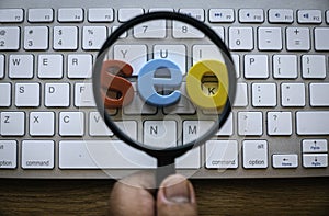 Search engine optimization concept. A hand holding magnifying glass magnify a word seo on a computer keyboard