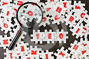 Search Engine Optimization, SEO concept, white puzzle jigsaw with alphabet building the word SEO at the center of dark chalkboard