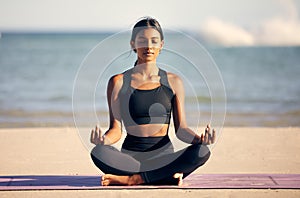 On the search for inner peace. Full length shot of an attractive young woman meditating on the beach.