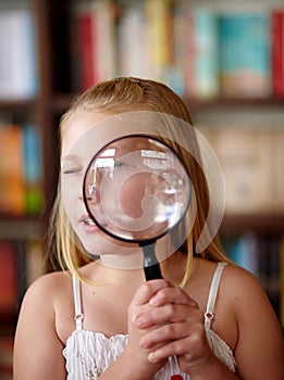 Search, portrait and a child with a magnifying glass in a library for education, learning or inspection. Looking, young