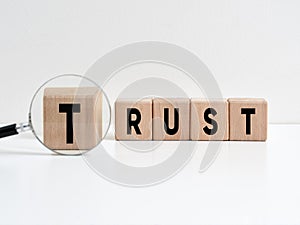 Searching for a business partnership based on trust. Trusted partner. The word trust on wooden cubes with a magnifying glass