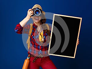 Tourist woman with blackboard and DSLR camera taking photo