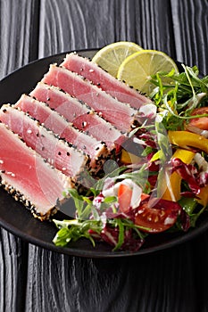 Seared ahi tuna coated sesame seeds with salad on black plate cl