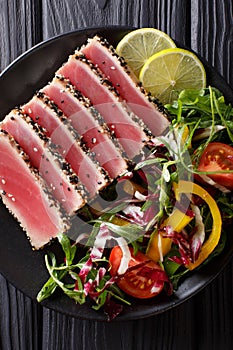 Seared ahi tuna coated sesame seeds with salad on black plate cl