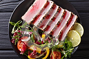 Seared ahi tuna coated sesame seeds with salad on black plate cl