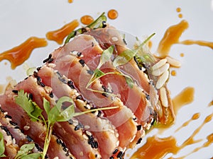 Seared ahi tuna slices on a bed of seaweed salad sprinkled with sesame seeds and oil and garnished with sprouts