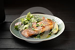 Seared salmon steak with lemon slices and vegetables served on blue plate