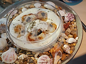 Seared scallops in a glass bowl in creamy souse sprinkled with dried nori photo