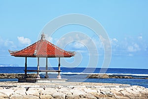 Seascape background with bright sun and traditional tent on Bali island, Indonesia