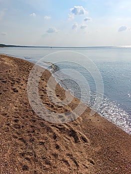 Seascape of the Baltic sea with calm water surface with yellow sand on the shore and clear blue sky above