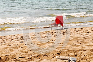 Seascape beach scene: white empty chair with red towel standing by the sea on sunny summer day.