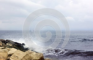 Seascape. Blue sky. Rocky beach. Sea. Waves are breaking on the shore. Bank is located on the left. Waves break on the shore.