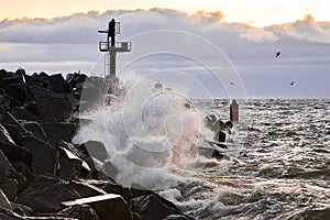 Seascape with a breakwater and a view of the water. Strong waves break against a protective structure made of concrete