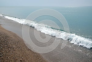 Seascape with calm sea surf with waves and sun reflecton on water on skyline