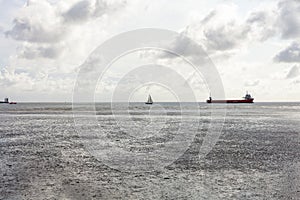 Seascape with cargo ships in the distance and cloudy sky