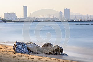 Seascape consist of rock on the Pattaya beach with Pattaya city as background