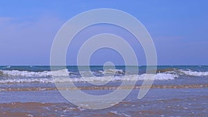 Seascape with curly long foamy rolling in tube waves in stormy sea at sunny day.