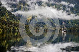 Seascape in Doubtful Sound Fiord, New Zealand, green costline and reflection in a wather, cloudy weather