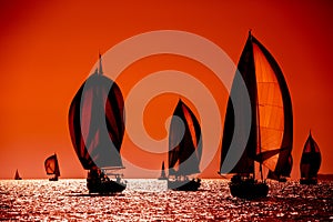 Sailing boats silhouette in the high sea on orange sunset