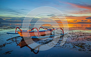 Seascape. Fisherman boat jukung. Traditional fishing boat at the beach during sunrise. Colorful sky. Amazing water reflection.