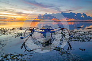 Seascape. Fisherman boat jukung. Traditional fishing boat at the beach during sunrise. Colorful sky. Amazing water reflection.