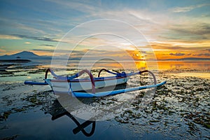 Seascape. Fisherman boat jukung. Traditional fishing boat at the beach during sunrise. Colorful sky. Amazing water reflection.