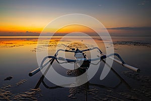 Seascape. Fisherman boat jukung. Traditional fishing boat at the beach during sunrise. Landscape. Water reflection. Slow shutter