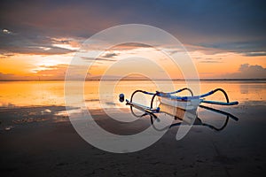 Seascape. Fisherman boat jukung. Traditional fishing boat at the beach during sunrise. Water reflection. Sanur beach, Bali,