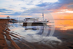Seascape. Fisherman boat jukung. Traditional fishing boat at the beach during sunrise. Water reflection. Sanur beach, Bali,