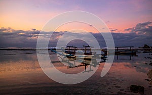 Seascape. Fisherman boat jukung. Traditional fishing boat at the beach during sunset. Cloudy sky. Amazing water reflection. Thomas