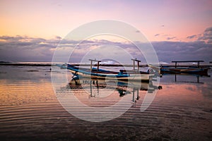 Seascape. Fisherman boat jukung. Traditional fishing boat at the beach during sunset. Cloudy sky. Amazing water reflection. Thomas