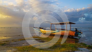 Seascape. Fisherman boat jukung. Traditional fishing boat at the beach during sunset. Cloudy sky. Water reflection. Thomas beach,
