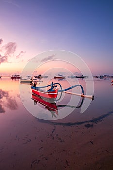 Seascape. Fisherman boat. Traditional Balinese boat jukung. Fishing boat at the beach during sunrise. Water reflection. Colorful