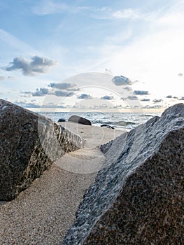 Seascape image of the sea with cloudy sky before sunset,  stones and  of light before sunset, beautiful sunny day and quiet sea.