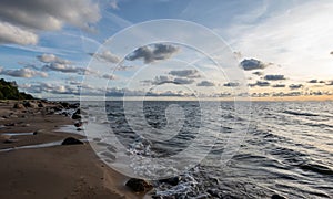 Seascape image of the sea with cloudy sky before sunset,  stones and  of light before sunset, beautiful sunny day and quiet sea.