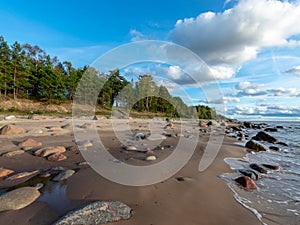 Seascape image of the sea with cloudy sky before sunset,  stones and  of light before sunset, beautiful sunny day and quiet sea.