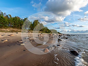 Seascape image of the sea with cloudy sky before sunset,  stones and  of light before sunset, beautiful sunny day and quiet sea.